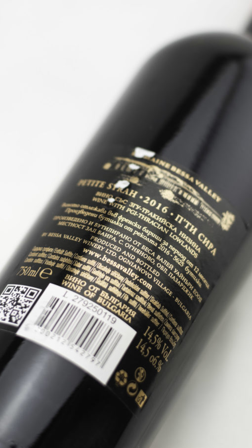 Detail fľaše bulharského vína Domaine Bessa Valley Petite Syrah s tmavorubínovou farbou vína.