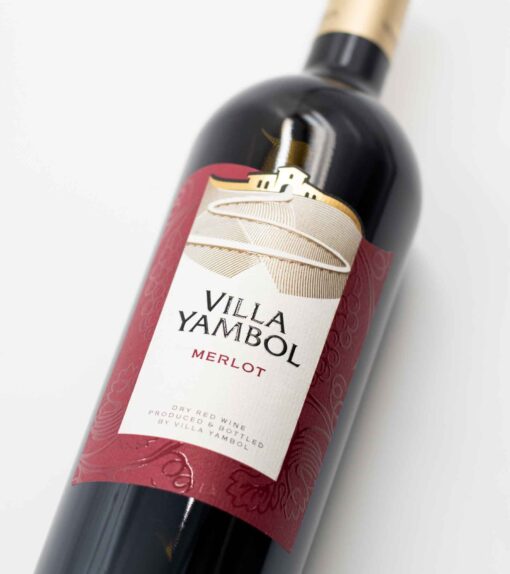 Detail fľaše bulharského vína Villa Yambol Merlot so sýtym rubínovým odtieňom vína.